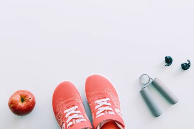 Kırmızı spor ayakkabılar, spor aletleri ve spor ayakkabıları, mavi arka planda elma. Sağlıklı yaşam ve eğitim kavramı, üst görüş, düz alan, kopyalama alanı.