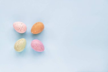 Mavi arka planda dört tane boyanmış Paskalya yumurtası, üst manzara, kopyalama alanı. Festivalsel arkaplan, minimal kompozisyon.