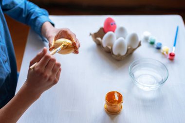 Beyaz bir masada yumurta boyayan bir kızın elleri. Paskalya konsepti. Seçici odak.