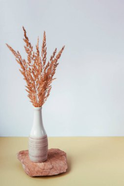 Bir taş tezgahının üzerinde kuru çimen olan vazo.