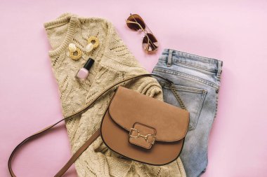 Kadınların moda dairesi pembe arka planda şık kıyafetler ve aksesuarlarla yatıyordu. Üst görünüm