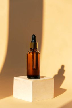 Ahşap bir kürsüde kahverengi cam şişedeki doğal yağ ya da serum. Alternatif tıp, güzellik ürünleri. Uzayı kopyala Gölgeli tarafsız arkaplan.