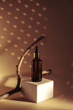 Ahşap bir kürsüde kahverengi cam şişedeki doğal yağ ya da serum. Alternatif tıp, güzellik ürünleri. Uzayı kopyala Arka planda güzel gölgeler.