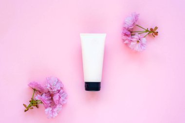 Pembe arka planda krema ve kiraz çiçeği. Doğal cilt bakımı kavramı. Üst manzara, düz yatış. Model.