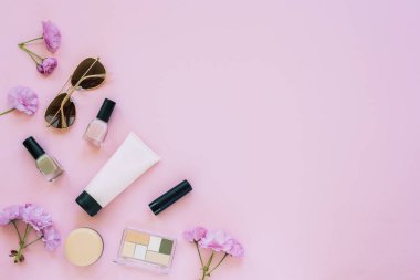 Makyaj ürünleri ve pembe arka planda güneş gözlüğü. Üst görünüm, düz görünüm, kopyalama alanı.