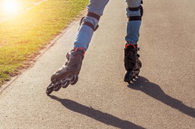 Kız güneşli bir günde parkta paten sürüyor..