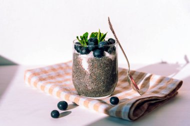 Kremalı Chia pudingi ve beyaz masanın üstünde bez peçete üzerine yaban mersini. Sağlıklı vejetaryen yemeği. Ön görünüm