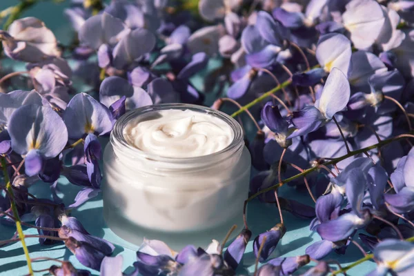 Cream jar and purple wisteria flowers background. Natural organic cosmetics concept — Stock Photo, Image