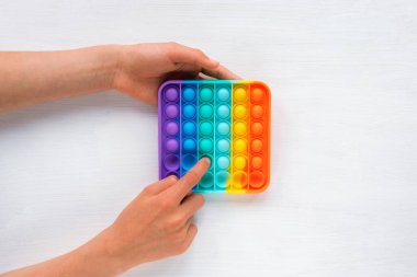 Childs 'ın elleri renkli poppit oyunuyla oynuyor. Kıpır kıpır. Üst manzara, düz uzanma