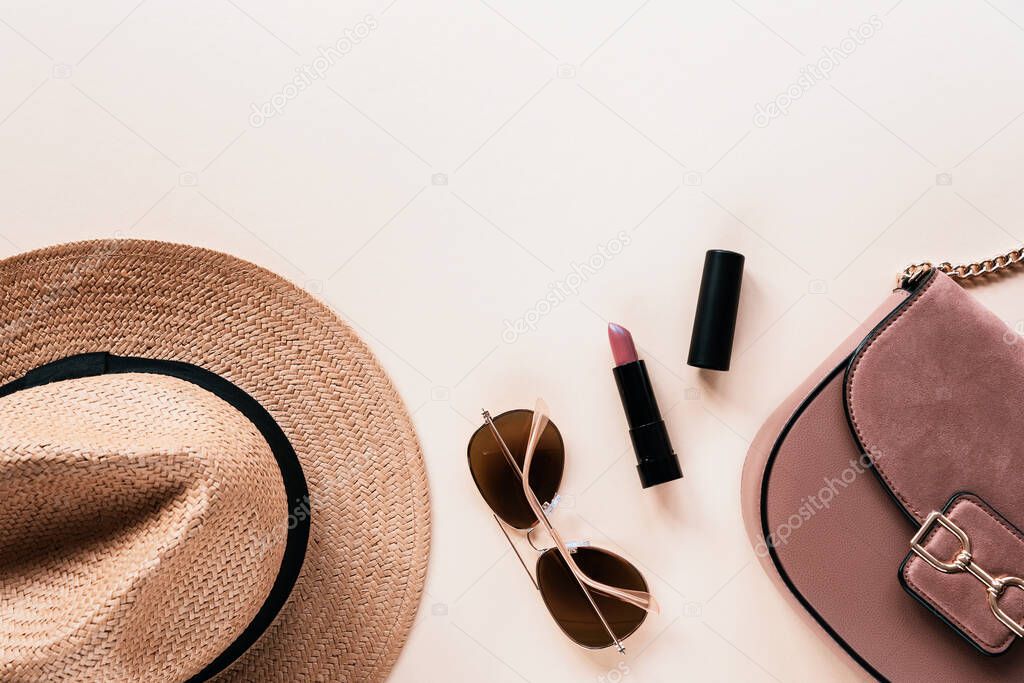 Flat lay with womens summer accessories on neutral background. Sunglasses, straw hat, lipstick and handbag. Top view, copy space
