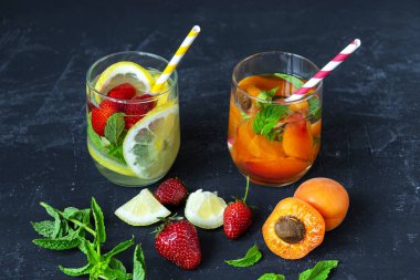 Yaz içeceklerini limonla, çilekle ve siyah arka planda kayısı dilimleriyle tazeliyorum..