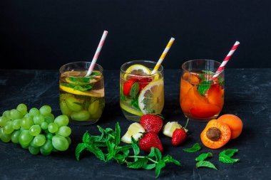 Sağlıklı yaz içkileri, siyah arka planda samanla bardakta limonata..