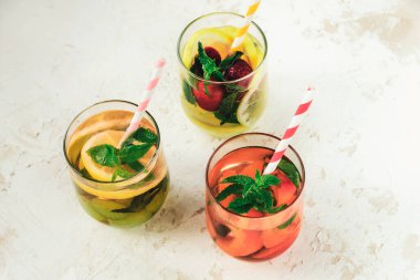 Three different summer healthy drinks, lemonade in glasses with straw on white background. Top view.