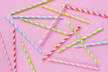 Pembe arka planda parti için pipet içmek. Kokteyller için renkli, tek kullanımlık, çevre dostu pipetlerin üst görüntüsü. Düz yatıyordu.