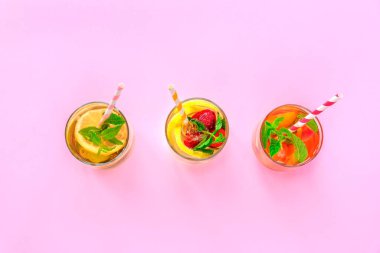 Three different colorful cold summer drinks on pink background. Top view, flat lay.