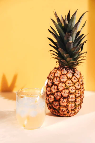 Jugo de piña con cubitos de hielo y fruta en el fondo de la pared amarilla. Enfoque selectivo — Foto de Stock