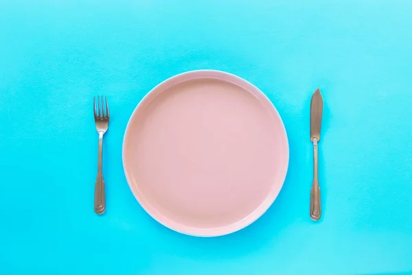 蓝色底座上有叉子和刀的空粉色盘子 节食的概念 — 图库照片