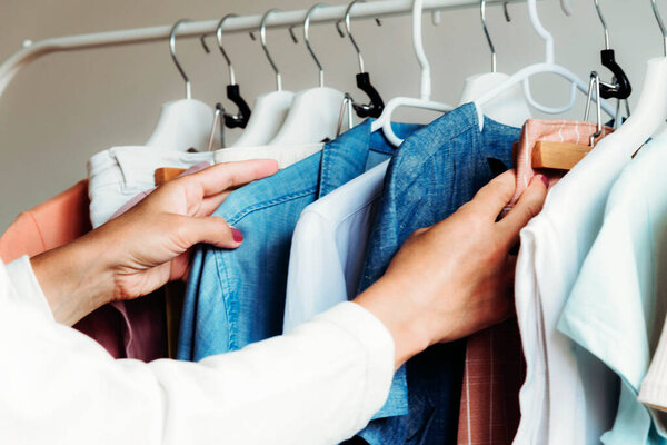 Женские руки выбирают повязку перед вешалкой. Мбаппе для магазинов, красоты, моды.