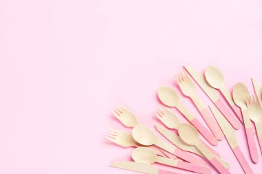 Tek kullanımlık bambu kaşıklar, çatallar ve bıçaklar pembe arka planda. Sıfır atık. Üst görünüm, düz görünüm, kopyalama alanı.
