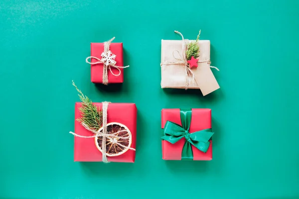 Yeşil arka planda dört adet kırmızı Noel hediyesi kutusu. Üst manzara, düz yatış. Yeni yıl konsepti — Stok fotoğraf