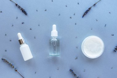 Lavanta doğal kozmetik kremi ya da maske kavanozda, serum ve mor arka planda çiçekli gerekli yağ. Aromaterapi, cilt bakım konsepti. Üst manzara, düz uzanma.
