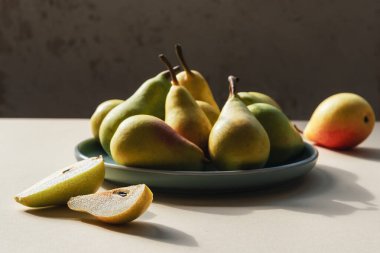 Bej masadaki yeşil tabakta taze armutlar. Sağlıklı vejetaryen yemeği. Kapat..