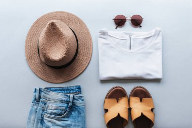 Kadınların yaz moda dairesi gri arka planda şık gündelik giysiler ve aksesuarlarla yatıyordu. Üst görünüm