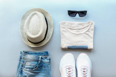 Kadınların yaz moda dairesi gri arka planda şık gündelik giysiler ve aksesuarlarla yatıyordu. Üst görünüm.