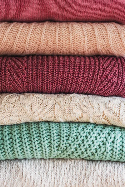 Stack of warm cozy knitted womens sweaters. Cozy autumn or winter clothes. Background — Stock Photo, Image