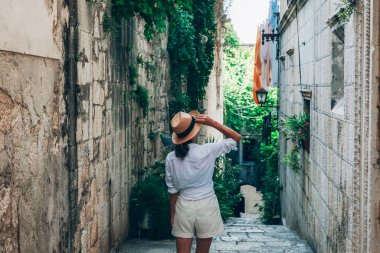 Hırvatistan 'ın Korcula kentinde güzel bir yaz gününde antik dar sokaklarda yürüyen kız turist