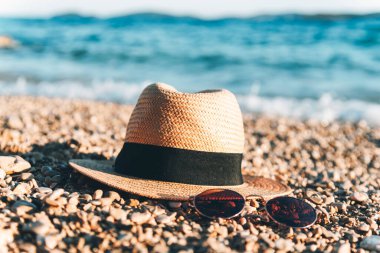 Sahilde güneş gözlüğü ve hasır şapka. Yaz tatili kavramı.