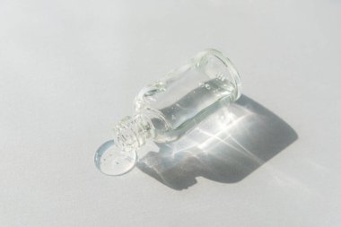 Bir şişe doğal cilt losyonu ya da sert gölgeli açık gri arka planda yüz serumu. Moda kişisel bakım ürünleri. Üst manzara, düz uzanma.