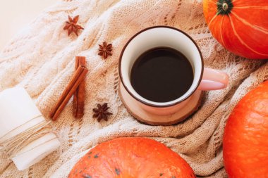 Masada bir fincan kahve, balkabağı, yıldız anason ve örülmüş bir süveterin üzerinde tarçın çubukları. Sonbahar konsepti, üst görünüm.