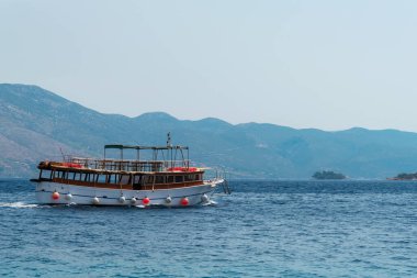 Turist teknesi adalar boyunca deniz kıyısında yol alır..