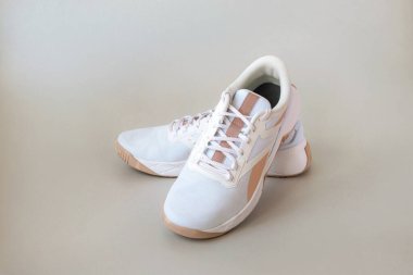 Açık renksiz arka planda bej çizgili beyaz spor ayakkabılar. Şık kadın spor ayakkabıları. Spor ve spor konsepti.