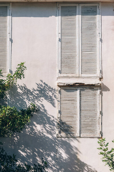 Традиционные средиземноморские окна и тени деревьев. Старый внешний вид здания.