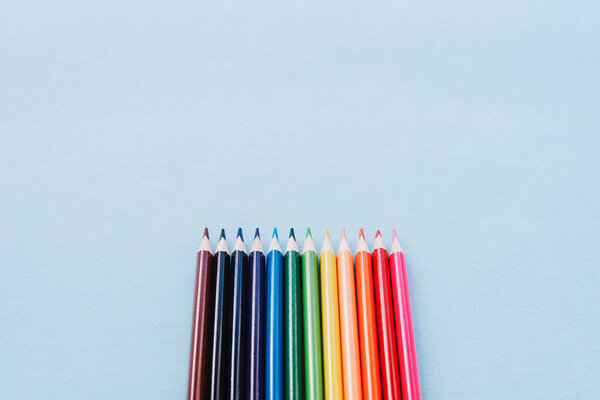 Color pencils on blue background, top view. School supplies close-up. Back to school concept. Copy space.