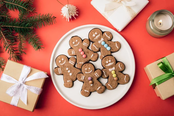 Renkli şekerli zencefilli kurabiyeler ve kırmızı arka planda Noel hediyeleri. Noel yatağı. Üst görünüm.
