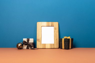 Hediye kutularıyla ahşap fotoğraf çerçevesi ve mavi ve kahverengi arka planda Noel mücevheri. Noel konsepti. Model.