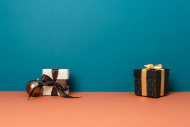 Mavi ve turuncu arka planda iki hediye kutusu ve kahverengi süs ve fotokopi alanı. Mutlu Noeller..