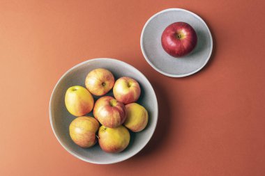 Kahverengi arka planda seramik kasede taze elmalar. Üst manzara, düz uzanma.