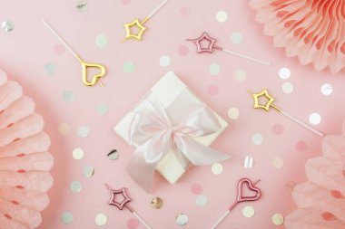 Hediye kutusu, mumlar, renkli konfeti ve mercan pembe arka planda kağıt mendiller. Doğum günü partisi konsepti. Üst manzara, düz uzanma.