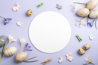 Paskalya yumurtaları ve tavşan süslemeleri. Mor arka planda daire şeklinde çiçekler. Üst görünüm, düz görünüm, model.