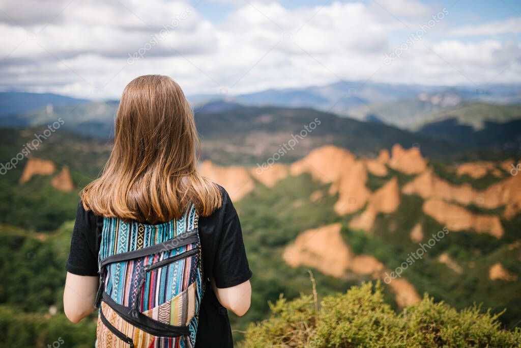Unrecognizable alternative woman looking at mountains with colorful backpack