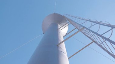 Su kulesi alçak bir açıdan çekildi, karmaşık detaylar ve açık mavi bir gökyüzü, yukarı doğru düzgün bir kamera hareketiyle etkileyici yüksekliği ve tasarımı vurguluyor.