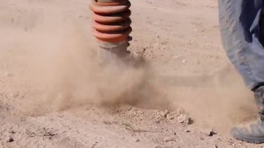 Toprak sıkıştırıcı gevşek toprak sıkıştırır, toz bulutları oluşturur ve etkili yol onarım sürecini gösterir, makinelerin gücünü ve araziye olan etkisini vurgular.