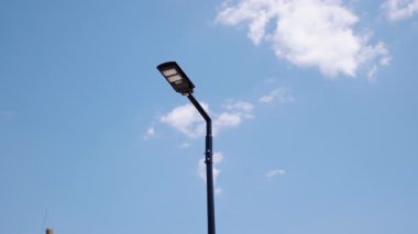 Modern sokak lambaları açık mavi gökyüzüne karşı yükselir, yenilikçi tasarımı ve işlevselliğini vurgular, sürdürülebilir aydınlatmayla kentsel çevreyi geliştirir.