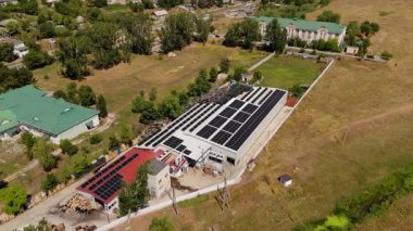 Hava perspektifi, verimli yeşillik ve açık alanlarla çevrili yenilenebilir enerji kullanımını vurgulayarak, güneş panelleri ile donatılmış fabrika çatısı yakalıyor ve çevre dostu teknolojiyi resmediyor.