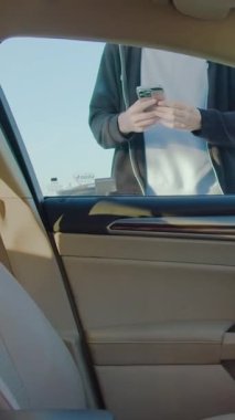 Kiralık aracın kilidini açmak için mobil uygulama ile etkileşim halinde olan erkek bireyler, kentsel taşımacılıkta kusursuz teknoloji entegrasyonunu ön plana çıkarırken, araç içi görünürde