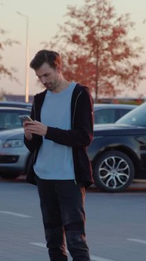 Erkek şahıs, işlek şehir otoparkındaki kiralık araca erişmek için mobil uygulama ile etkileşim halinde, yenilikler ve kentsel hareketliliğin kolaylığı vurgulanıyor